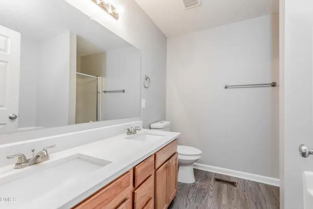 a bathroom with a double vanity sink toilet and a mirror