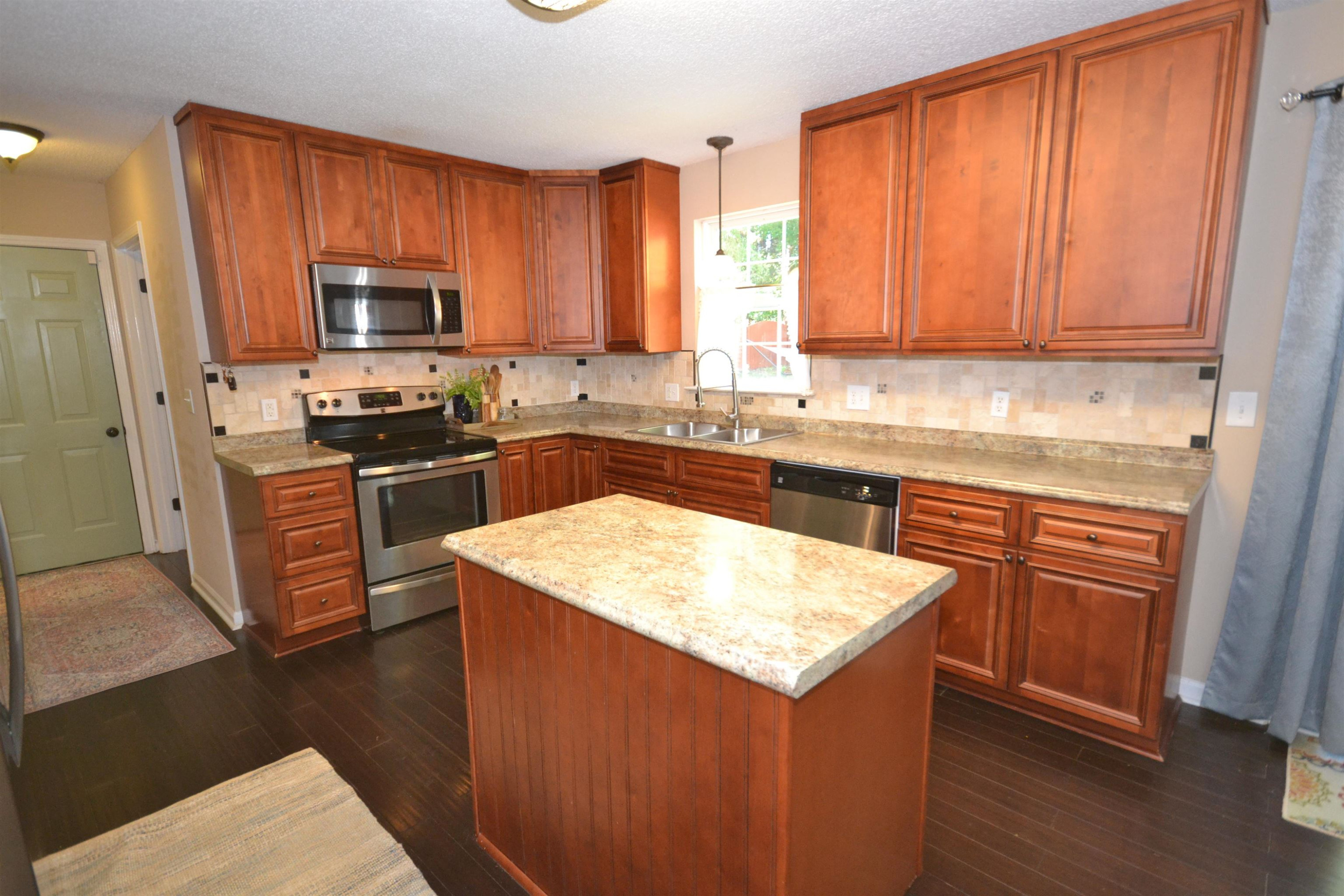 5501 Cardinal Grove Boulevard Raleigh, NC 27616 - Photo 7 of 37 a kitchen with stainless steel appliances granite countertop wooden cabinets a stove top oven a sink and dishwasher with wooden floor