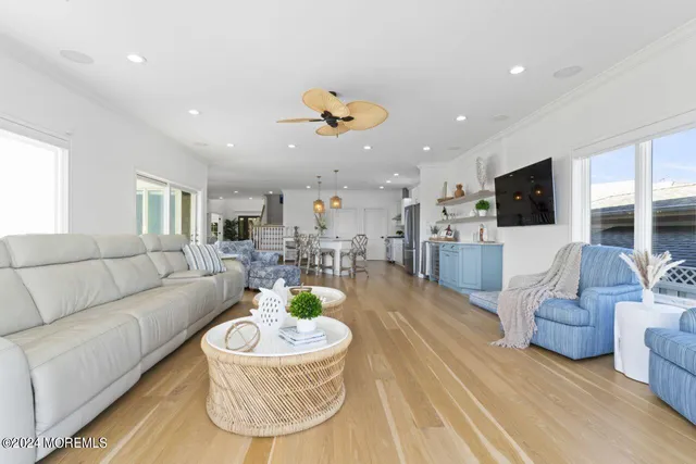 a living room with couches kitchen view and a chandelier