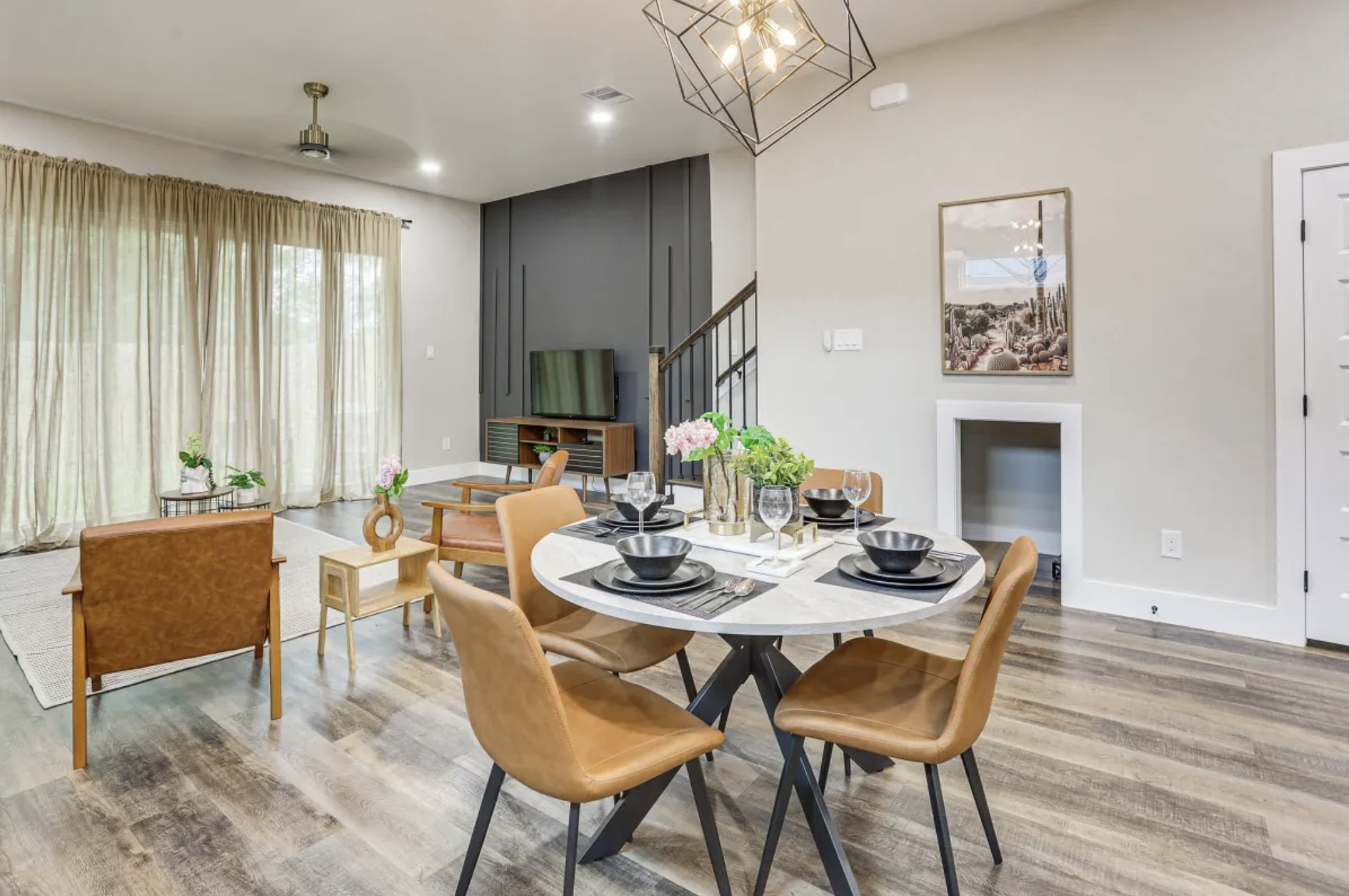 3727 Dreyfus Street Houston, TX 77021 - Photo 2 of 17 This modern open-concept living and dining area features sleek vinyl flooring. Large windows with sheer curtains offer natural light, complemented by tasteful decor and a unique geometric light fixture.