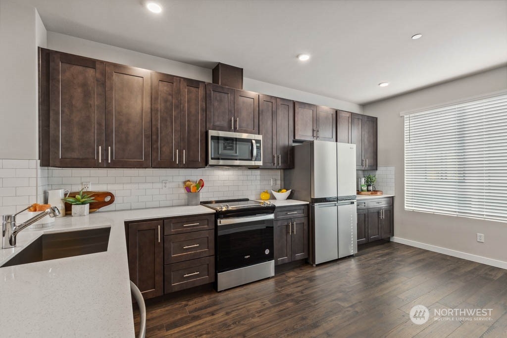 9616 19th Avenue Southeast, Unit E Everett, WA 98208 - Photo 7 of 17 a kitchen with stainless steel appliances a stove a sink a refrigerator cabinets and wooden floor