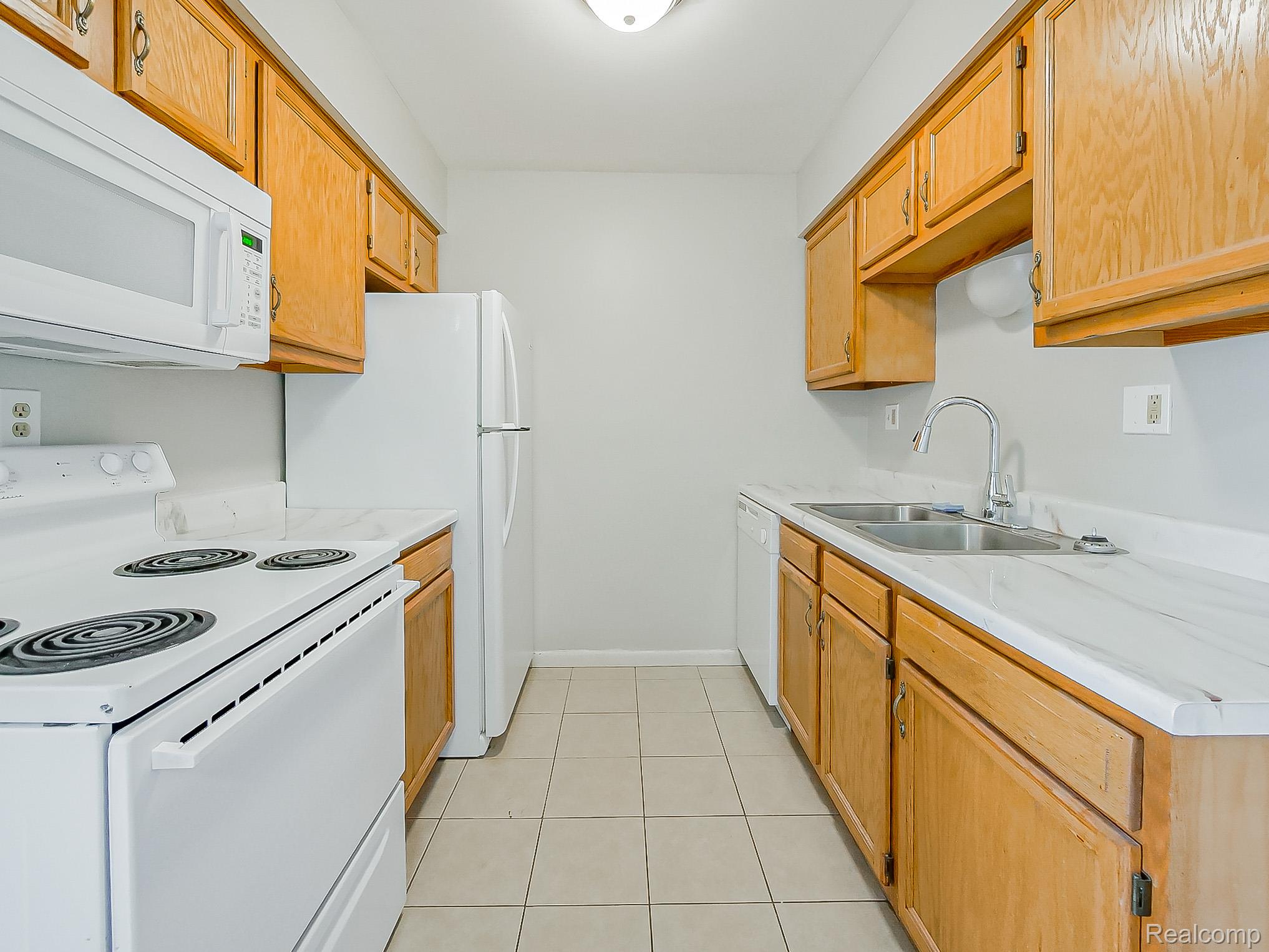 125 East Van Riper Road, Unit 5 Fowlerville, MI 48836 - Photo 8 of 23 Kitchen with white appliances, light countertops, and light tile patterned flooring
