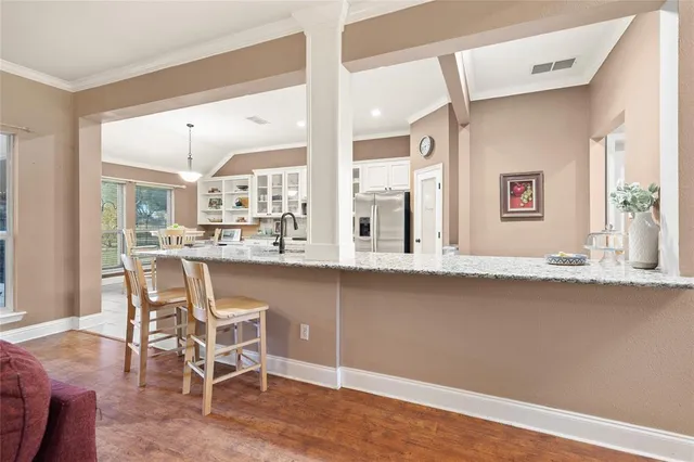 a dining hall with stainless steel appliances granite countertop a stove and a wooden floors
