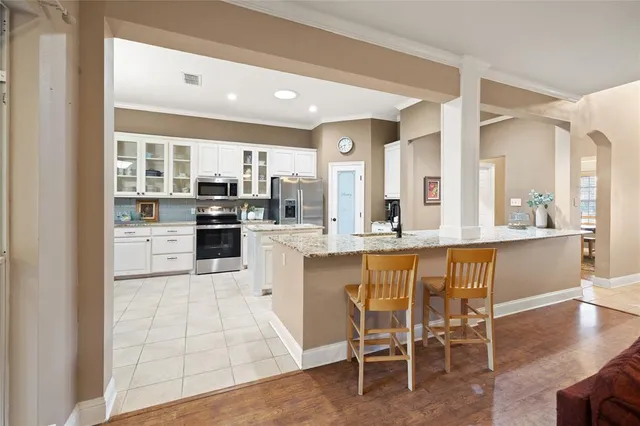 a large kitchen with kitchen island granite countertop lots of white cabinets and stainless steel appliances