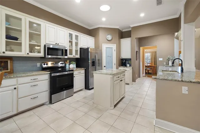 a open kitchen with stainless steel appliances granite countertop a stove top oven a sink a dining table and chairs