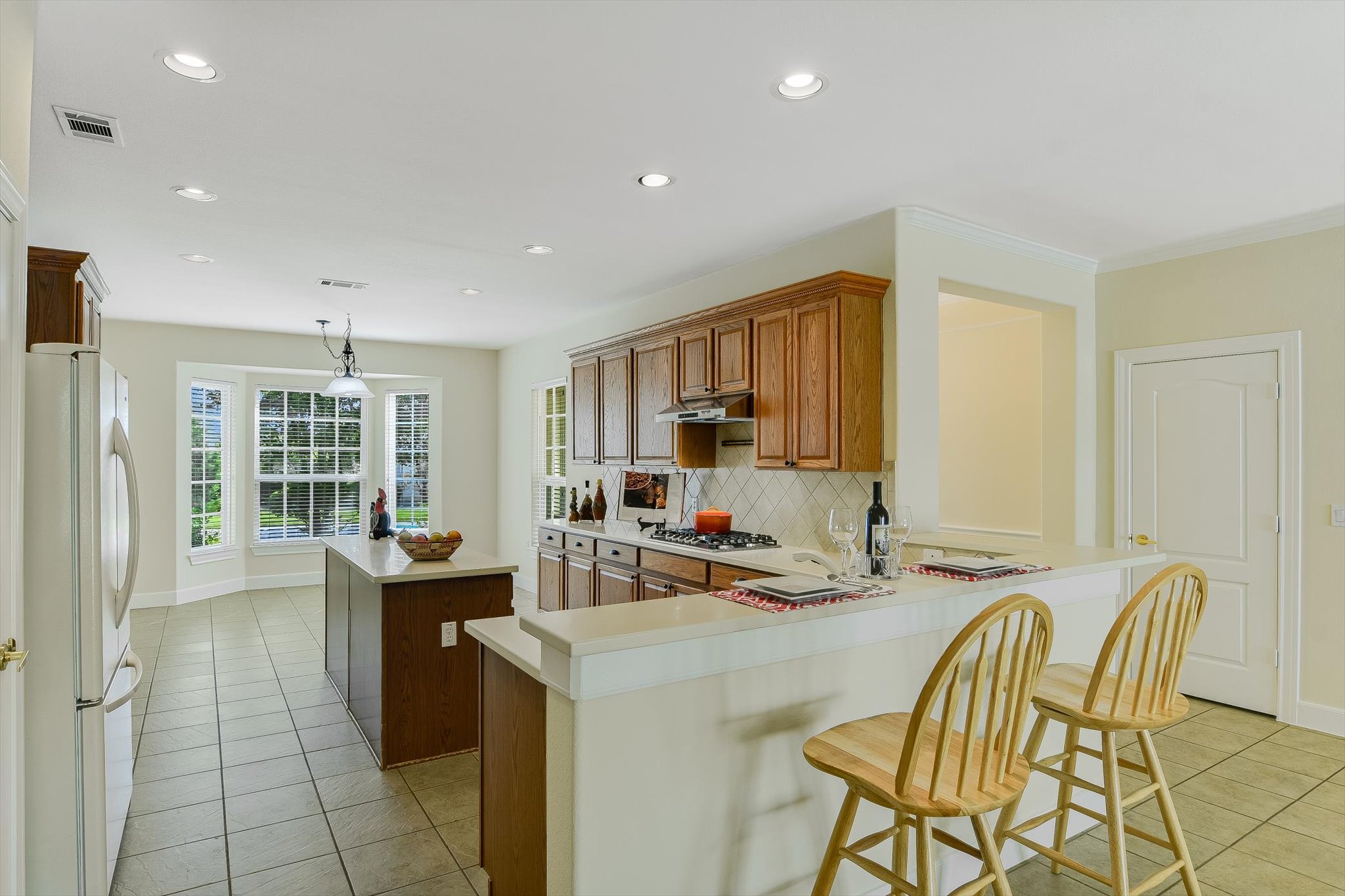 603 Rio Grande Loop Georgetown, TX 78633 - Photo 10 of 27 Kitchen featuring a center island, backsplash, freestanding refrigerator, light tile patterned flooring, and brown cabinets