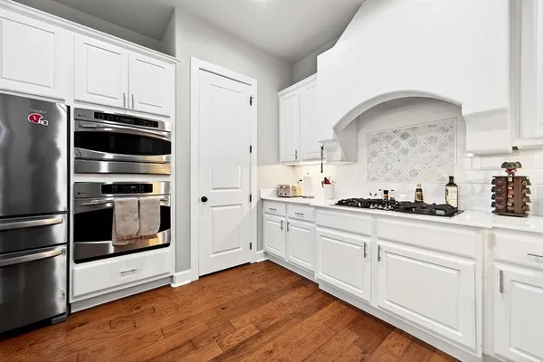 a kitchen with granite countertop white cabinets and stainless steel appliances
