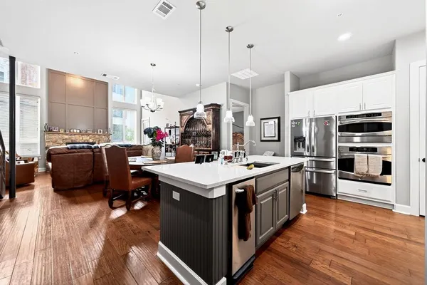 a kitchen with kitchen island a stove a sink dishwasher a refrigerator and a dining table with wooden floor
