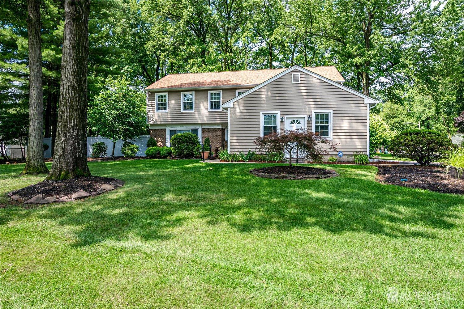 a front view of a house with a garden and trees