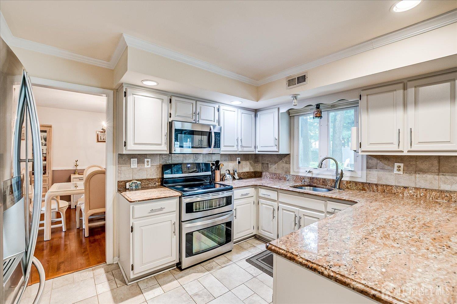 2 Pine Ridge Drive Edison, NJ 08820 - Photo 15 of 50 a kitchen with stainless steel appliances granite countertop a stove top oven a sink a dining table and chairs