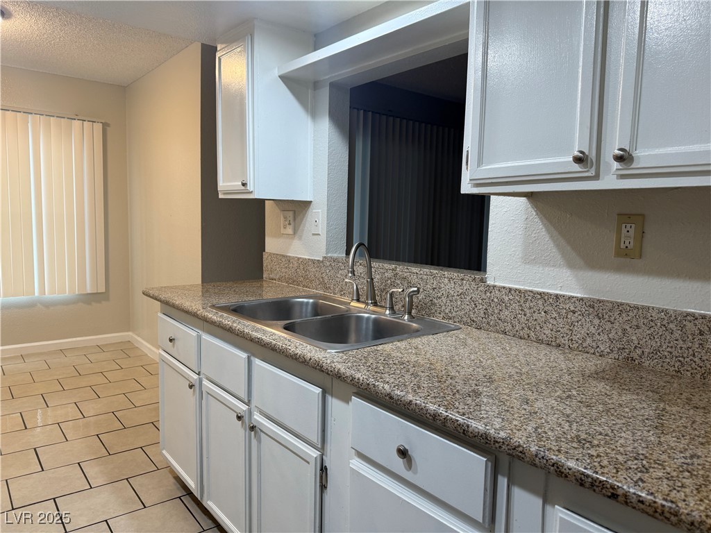 2853 Wheelwright Drive, Unit A Las Vegas, NV 89121 - Photo 3 of 12 Kitchen featuring white cabinetry, light tile patterned flooring, and a textured ceiling
