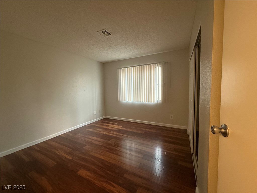 2853 Wheelwright Drive, Unit A Las Vegas, NV 89121 - Photo 8 of 12 Unfurnished room with dark wood-type flooring and a textured ceiling