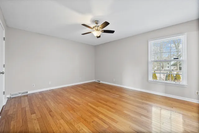 an empty room with a window and a ceiling fan