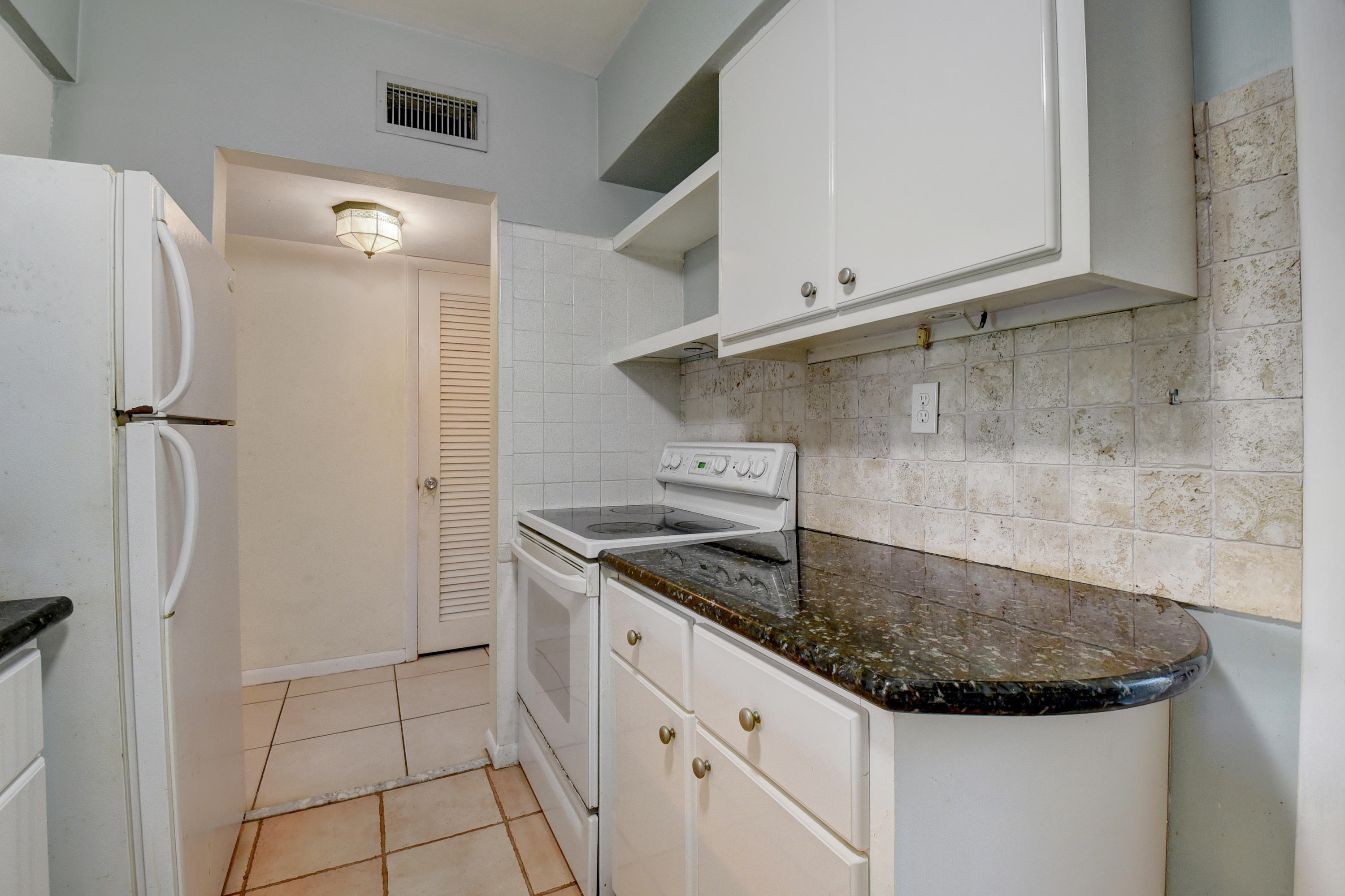 2700 Banyan Road, Unit 2C Boca Raton, FL 33432 - Photo 22 of 33 a kitchen with stainless steel appliances granite countertop a sink and a refrigerator