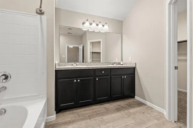 a bathroom with a granite countertop sink a large mirror and a bathtub