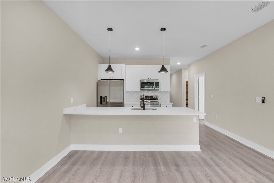 12208 Tetzel Avenue Port Charlotte, FL 33981 - Photo 25 of 45 a large kitchen with stainless steel appliances a large counter top a sink a refrigerator and a window