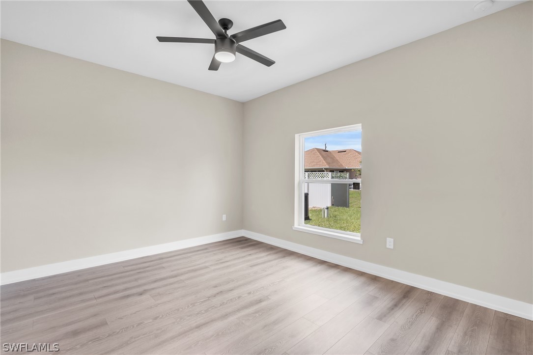 12208 Tetzel Avenue Port Charlotte, FL 33981 - Photo 31 of 45 an empty room with wooden floor ceiling fan and windows