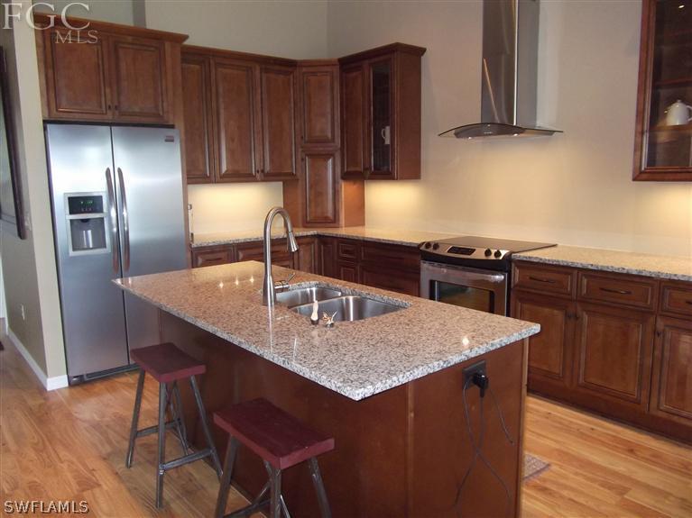 13155 Heather Ridge Loop Fort Myers, FL 33966 - Photo 8 of 25 a kitchen with stainless steel appliances granite countertop a sink a stove a refrigerator and wooden cabinets