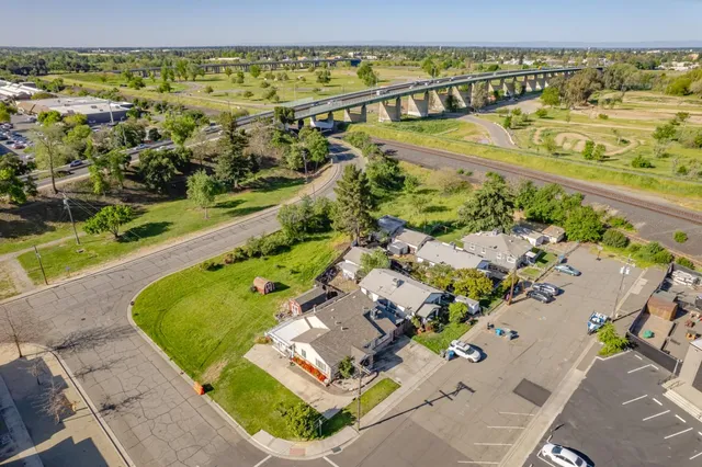 a view of a white house with a big yard potted plants and large tree