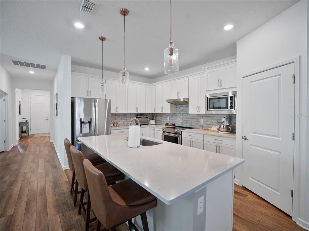 8741 Southwest 61st Loop Ocala, FL 34481 - Photo 5 of 60 a kitchen with stainless steel appliances granite countertop a sink a stove a refrigerator and white cabinets with wooden floor