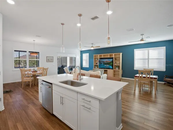 a kitchen with stainless steel appliances a stove a sink a microwave a refrigerator a sink and white cabinets