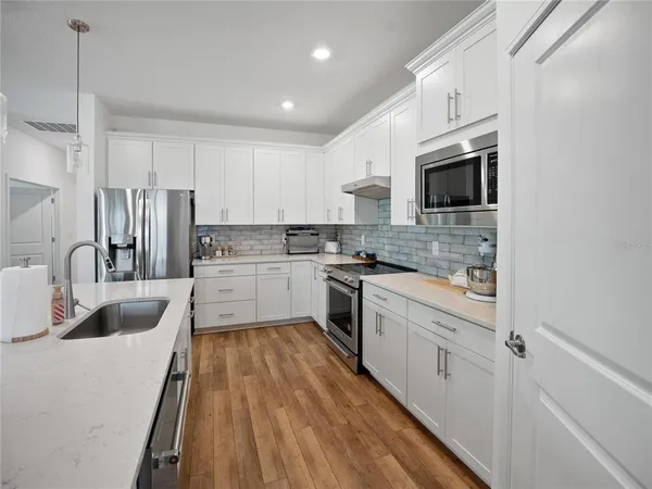 a kitchen with stainless steel appliances granite countertop a sink a stove a refrigerator with a dining table and chairs