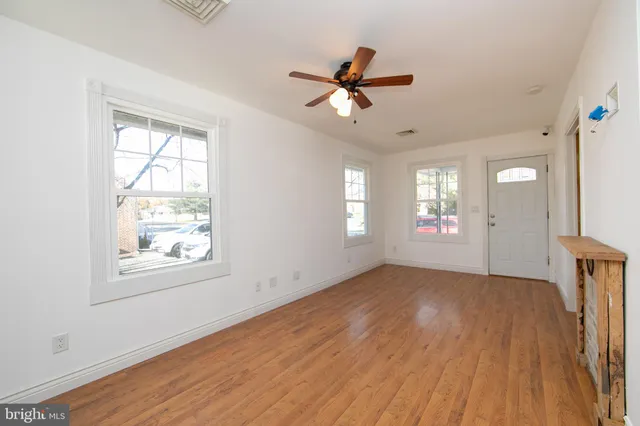 a view of empty room with wooden floor and fan