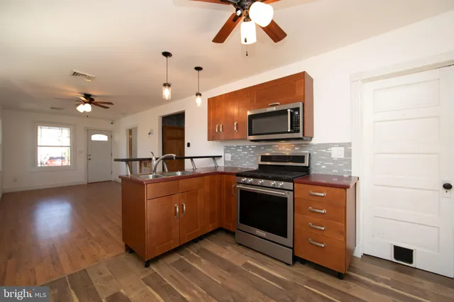 a kitchen with kitchen island granite countertop a stove top oven a sink a counter space and cabinets