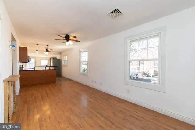 a view of a kitchen and an empty room with a window