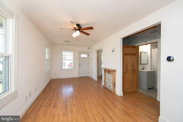 a view of empty room with wooden floor and fan