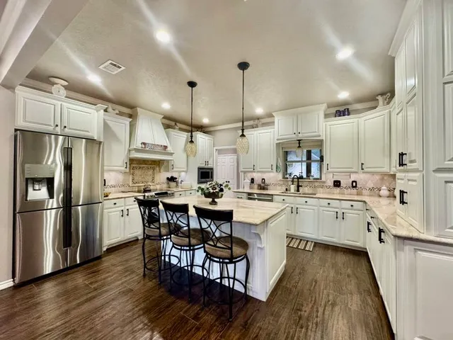 a kitchen with appliances a sink a center island and a counter top space