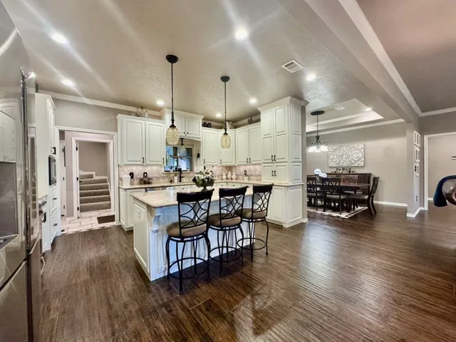 a kitchen with stainless steel appliances kitchen island granite countertop a stove a refrigerator and a dining table with wooden floor