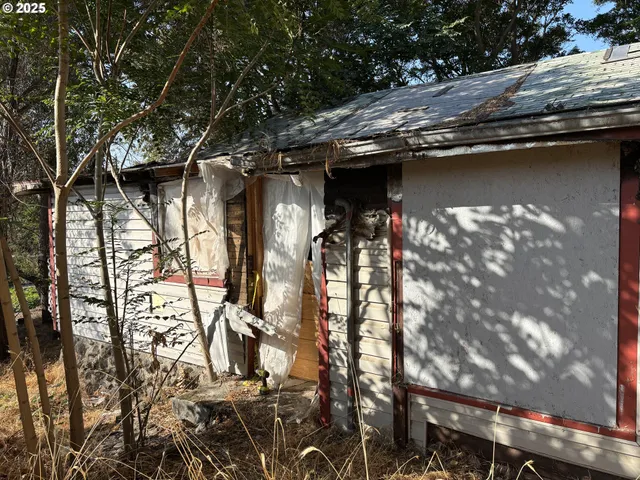 a backyard of a house with wooden fence and large trees