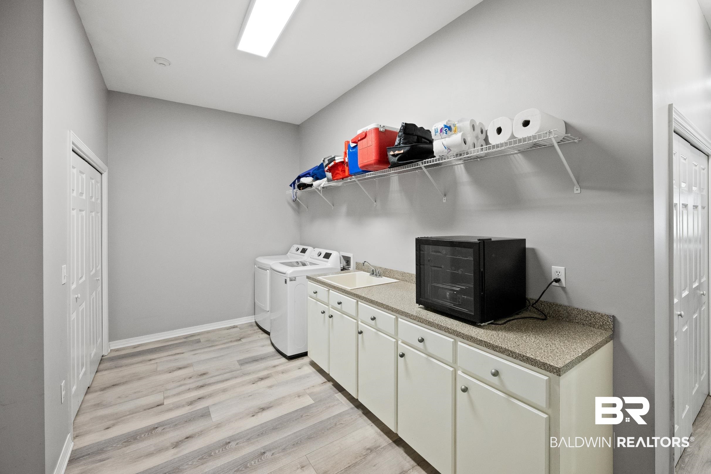 8585 Bay Harbor Road Elberta, AL 36530 - Photo 20 of 51 Laundry room featuring independent washer and dryer, light wood-style flooring, and cabinet space