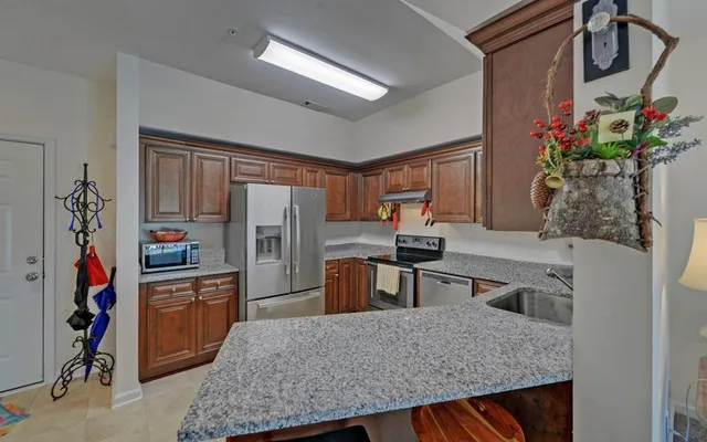 a kitchen with granite countertop a refrigerator a stove top oven a sink and dishwasher