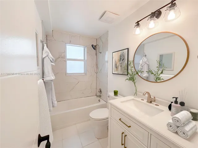 a bathroom with a granite countertop toilet sink and mirror