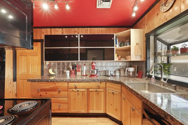 a kitchen with granite countertop a sink a stove and a wooden cabinets