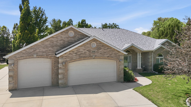 2190 750 West Perry, UT 84302 - Photo 2 of 42 Brick exterior featuring a two-car garage with arched entrances, a concrete driveway, and a curved sidewalk leading to the main entrance