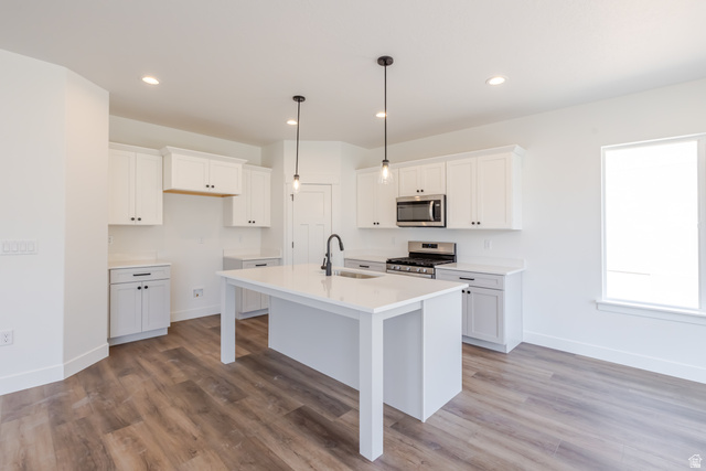195 West Harmony Rdg Parkway, Unit 601 Mapleton, UT 84664 - Photo 6 of 23 Modern kitchen featuring white shaker cabinetry, stainless steel appliances, a center island with sink and pendant lighting, wood-finish flooring, and recessed ceiling lights
