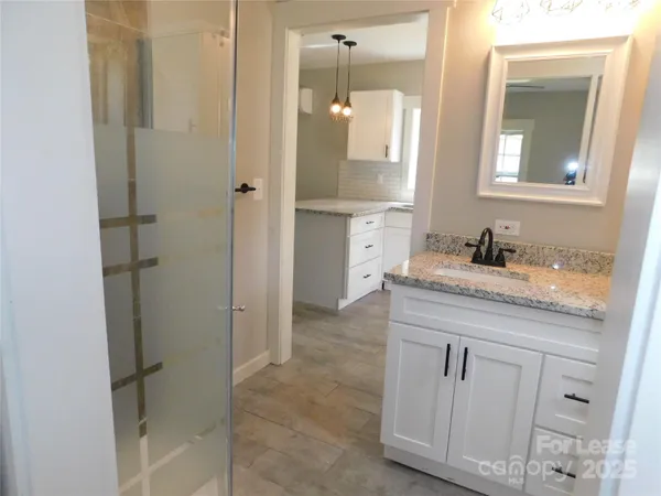 a bathroom with a granite countertop sink two mirror and shower