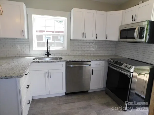 a kitchen with granite countertop a sink stove and microwave