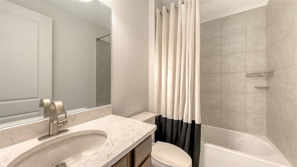 11869 Richmond Trail Parrish, FL 34219 - Photo 48 of 68 a bathroom with a granite countertop sink toilet a mirror and bathtub