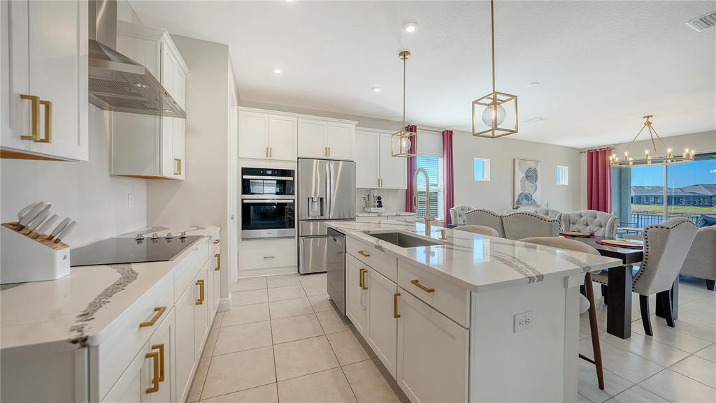 11869 Richmond Trail Parrish, FL 34219 - Photo 10 of 68 a large white kitchen with stainless steel appliances kitchen island granite countertop a sink a stove and a refrigerator