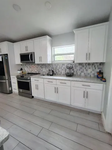a kitchen with granite countertop white cabinets and white appliances