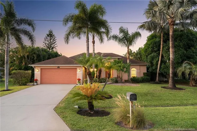 a front view of a house with garden and trees