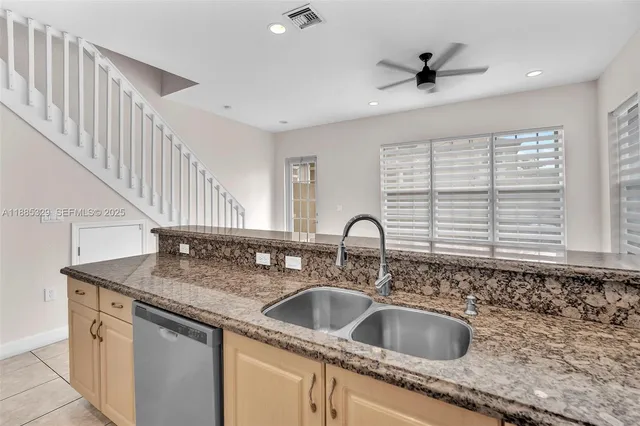 a kitchen with granite countertop a sink and a white wooden cabinets