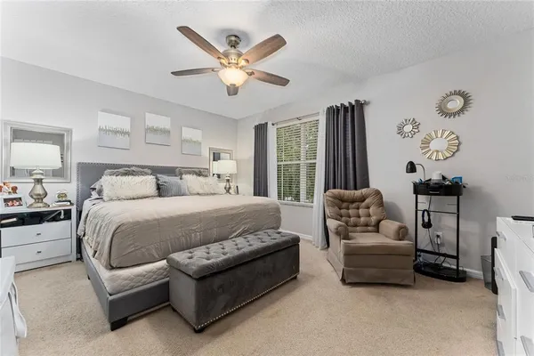 a spacious bedroom with a bed a couch and a chandelier