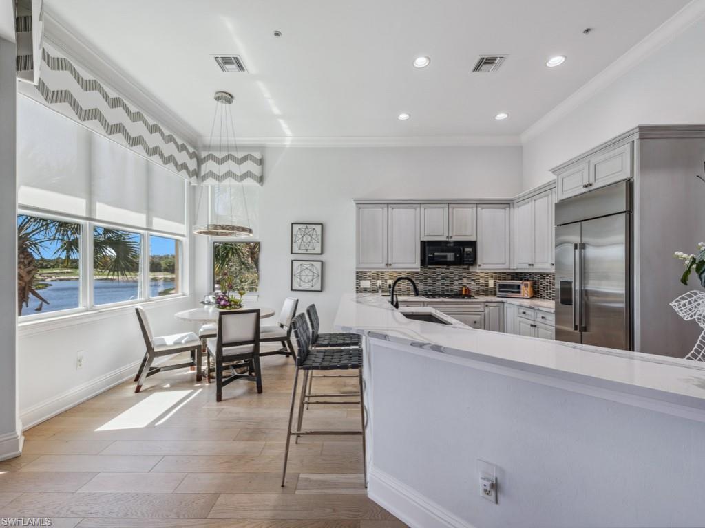 16985 Porta Vecchio Way, Unit 202 Naples, FL 34110 - Photo 10 of 50 a large open kitchen with stainless steel appliances granite countertop a stove and a refrigerator with cabinets