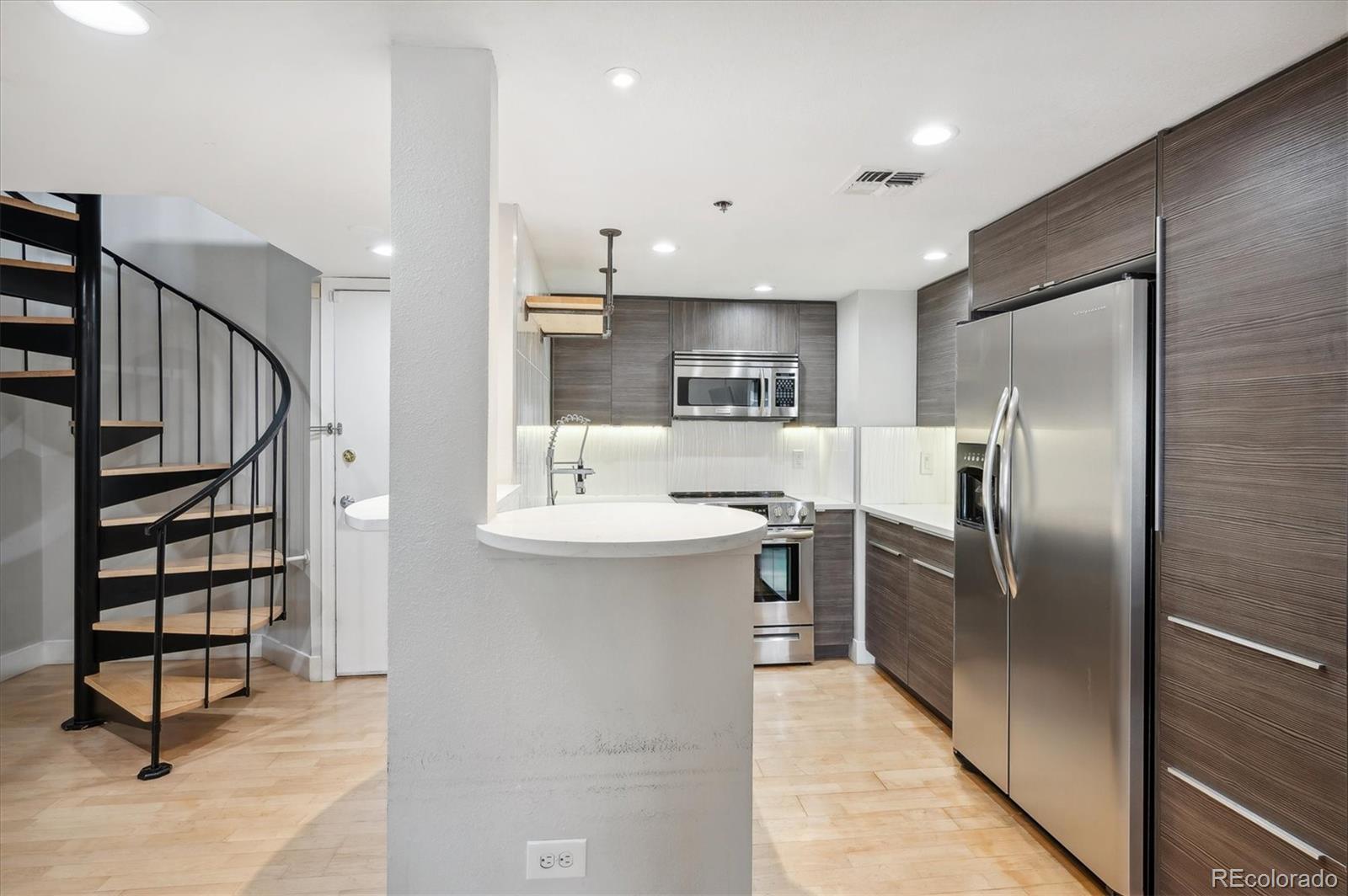 350 Detroit Street, Unit 413 Denver, CO 80206 - Photo 6 of 24 a kitchen with kitchen island a counter top space cabinets and stainless steel appliances