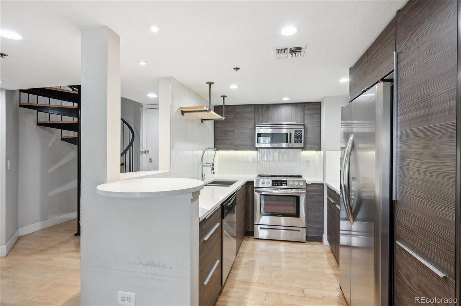 350 Detroit Street, Unit 413 Denver, CO 80206 - Photo 7 of 24 a kitchen with kitchen island a sink stainless steel appliances and cabinets